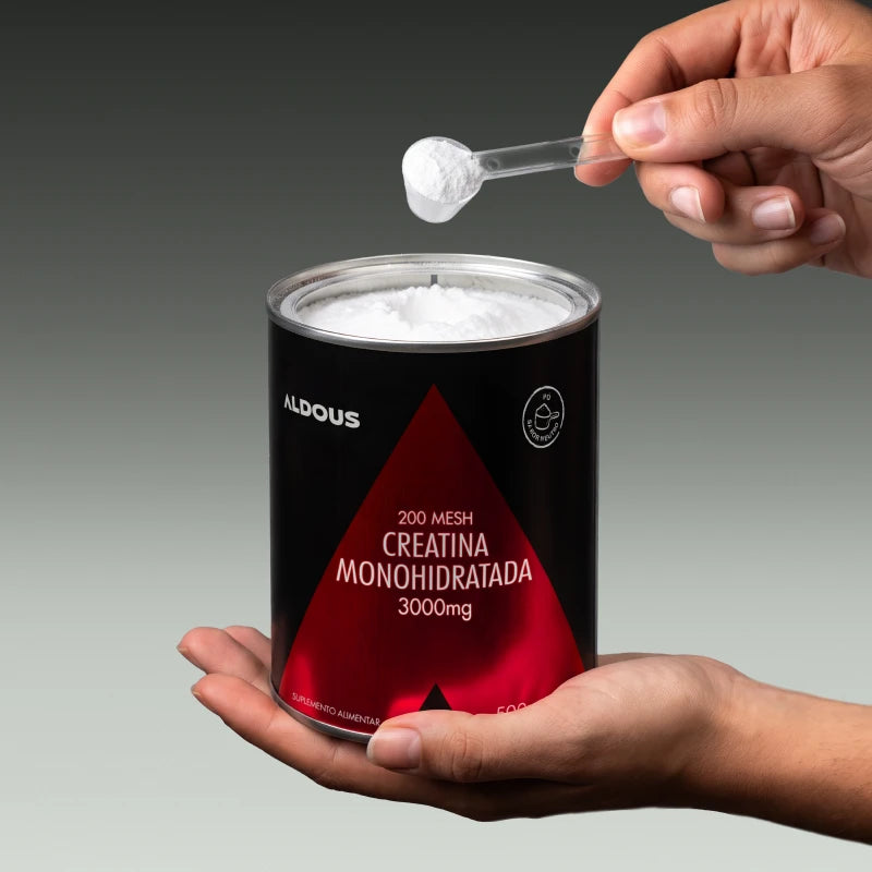 Imagen de unas manos cogiendo un cacito de creatina del bote de la Creatina Aldous